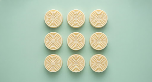 White chocolate bonbons with maze-like patterns on a mint surface.