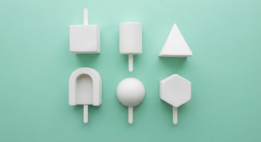 Geometric white ice pop molds arranged on a mint background.