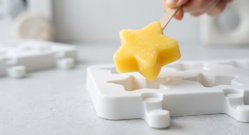 A yellow star ice pop being released from a white mold.